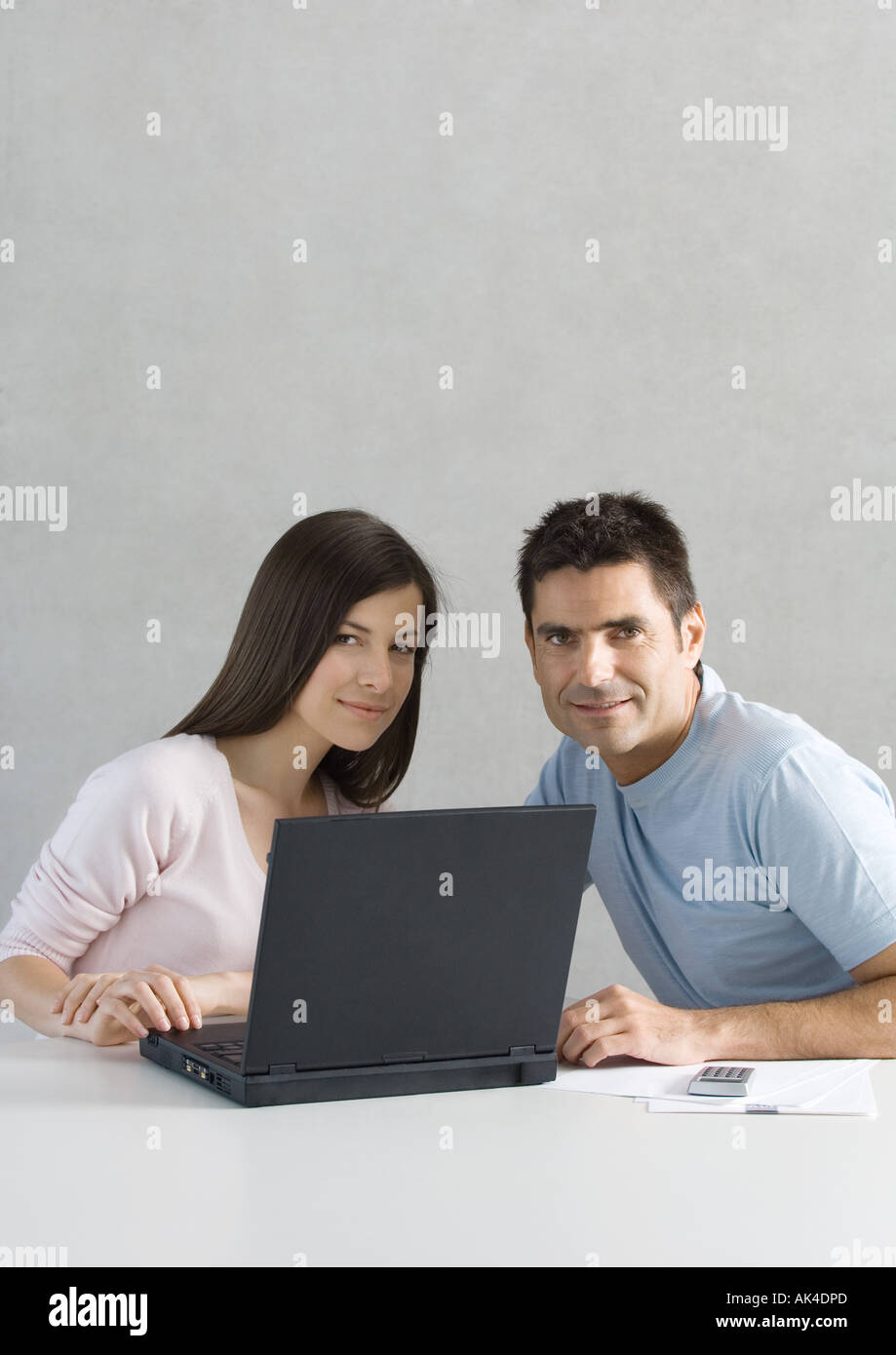 Couple using laptop, smiling at camera Stock Photo