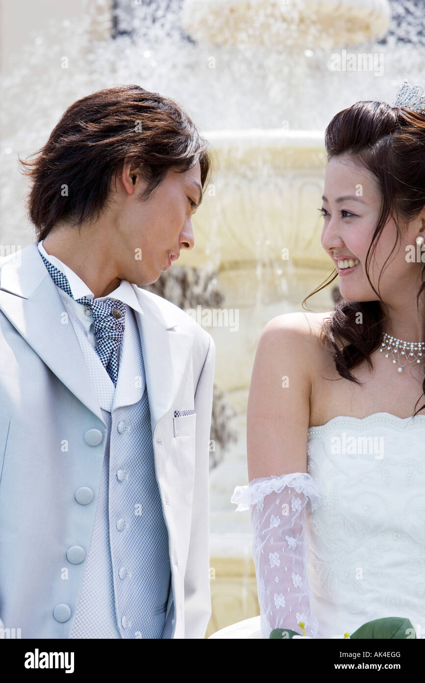 Bride and groom sitting in front of fountain, close-up Stock Photo - Alamy