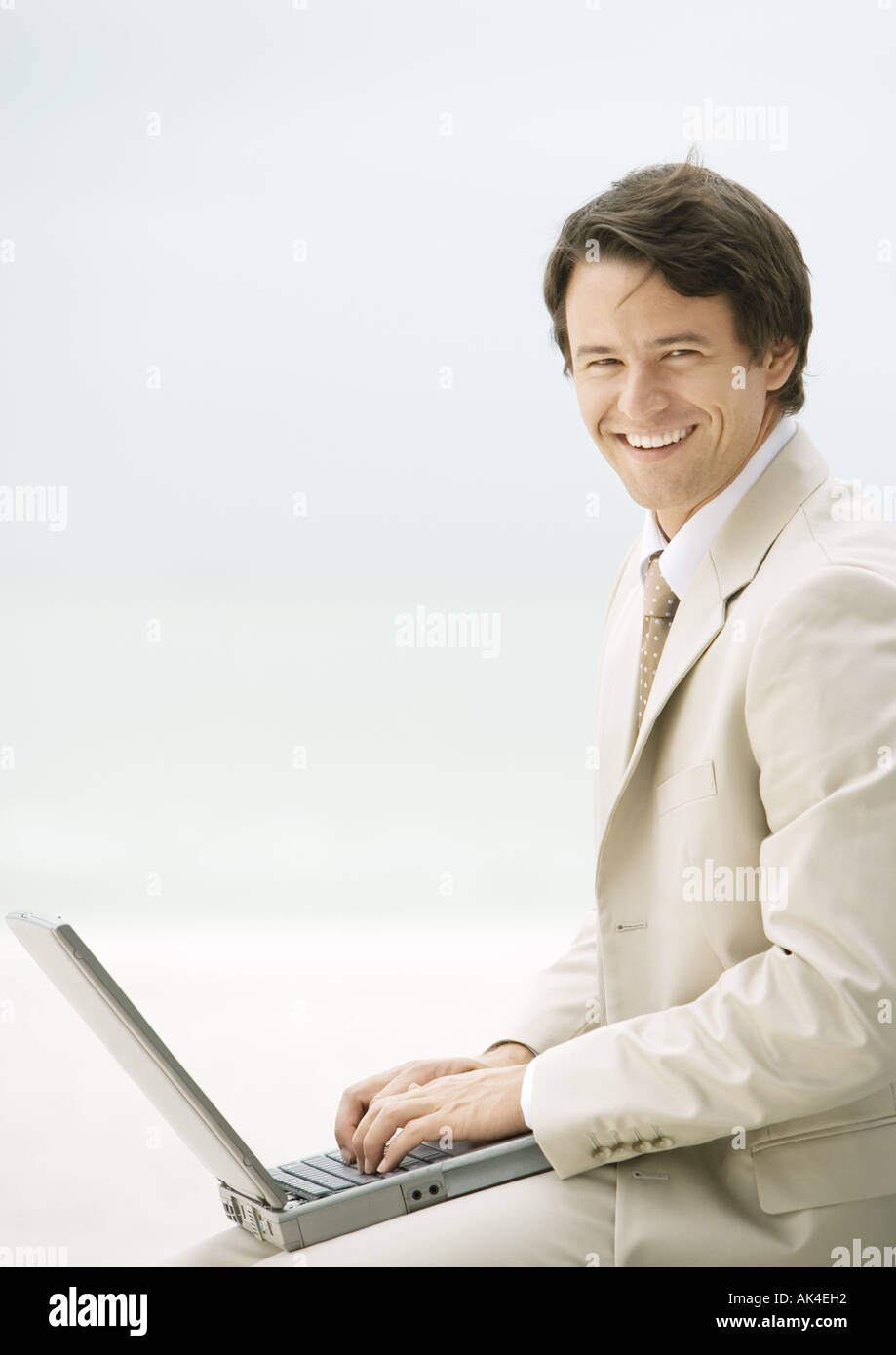 Businessman using laptop, smiling at camera Stock Photo