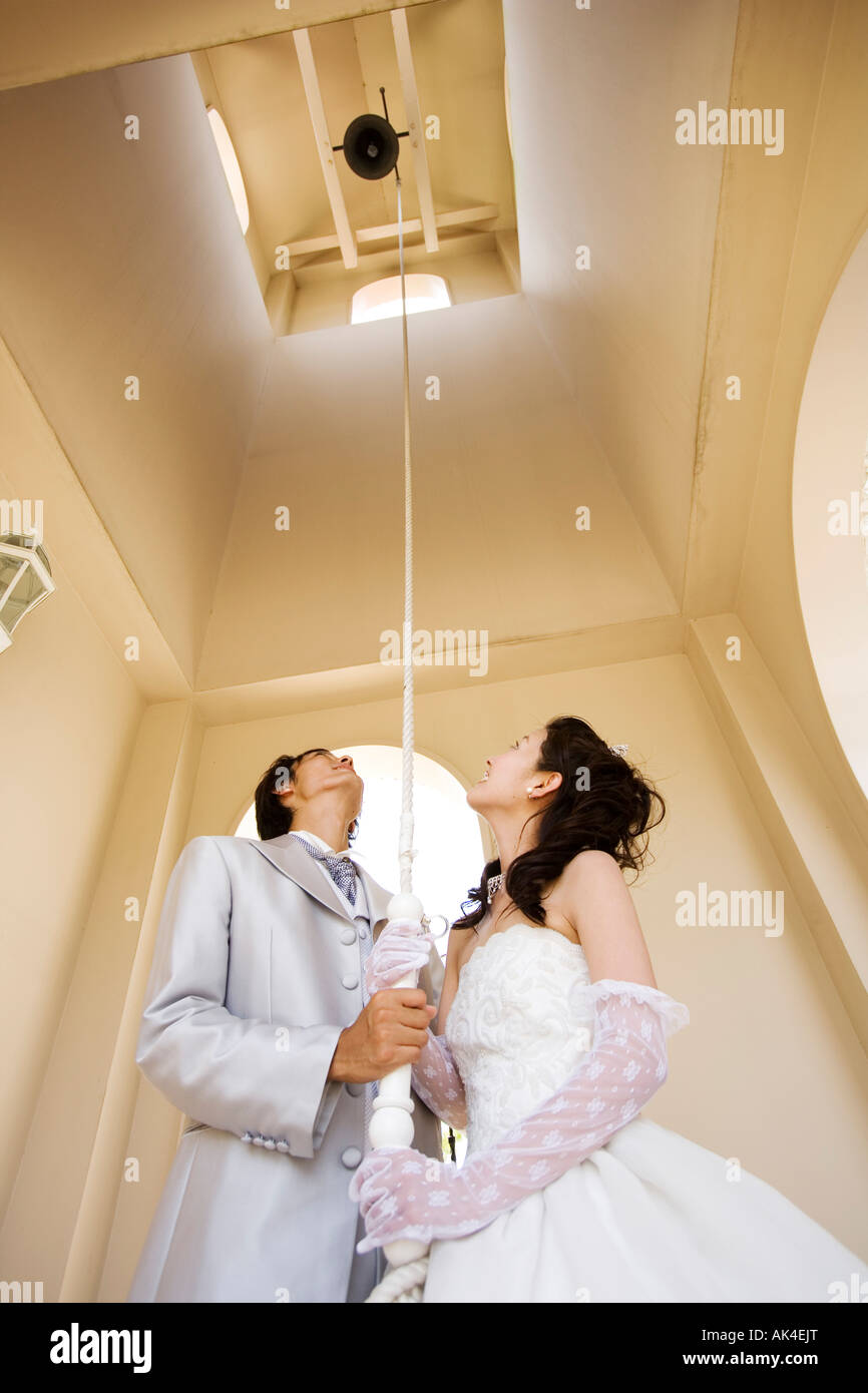 Bride and groom pulling the rope of bell Stock Photo - Alamy