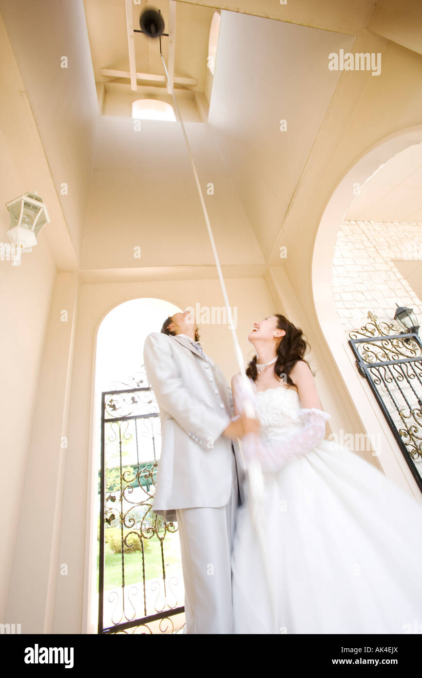 Bride and groom pulling the rope of bell Stock Photo - Alamy