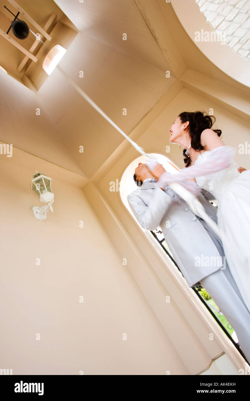 Bride and groom pulling the rope of bell, low angle view Stock Photo ...