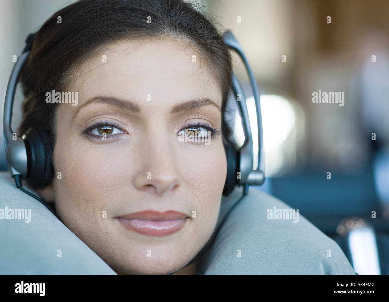 Woman wearing headphones and using neck pillow, close-up Stock Photo