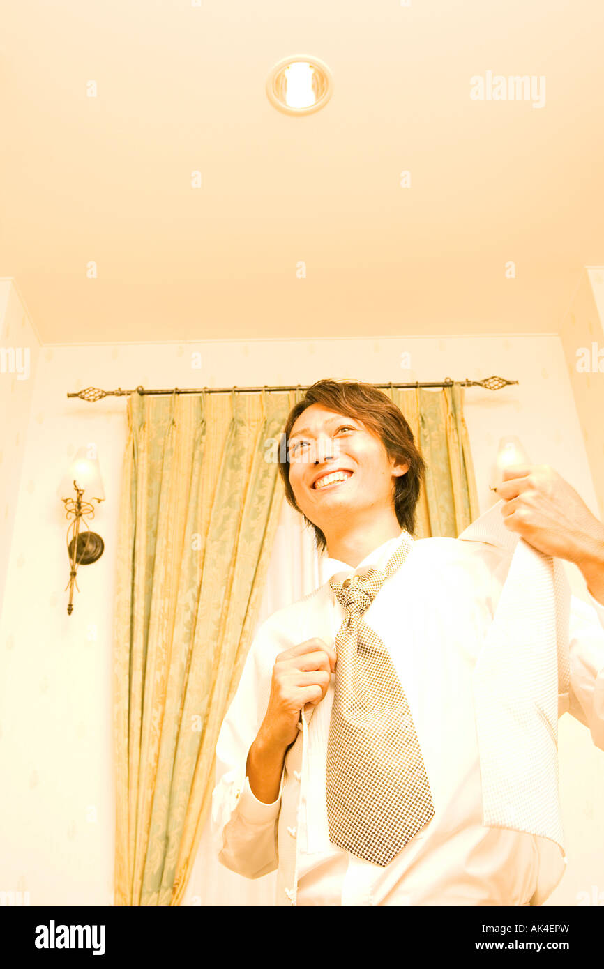 Young man putting on suit, smiling, low angle view Stock Photo - Alamy