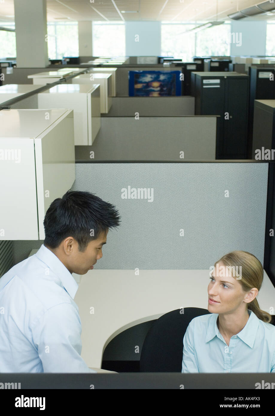 Two office workers talking in cubicle Stock Photo