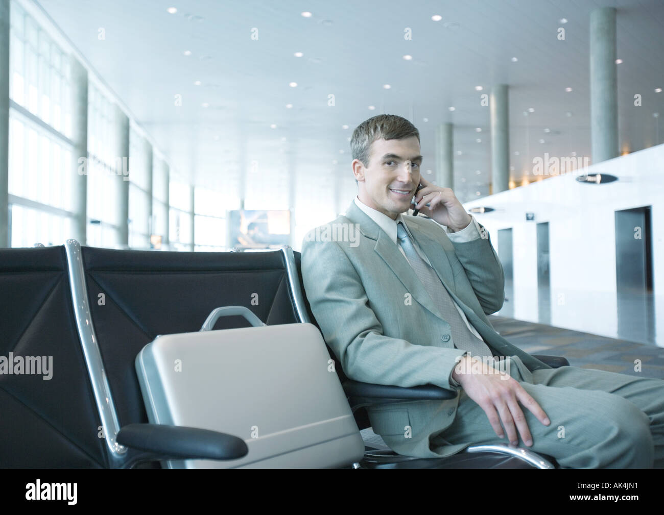Businessman sitting in airport lounge, using cell phone Stock Photo