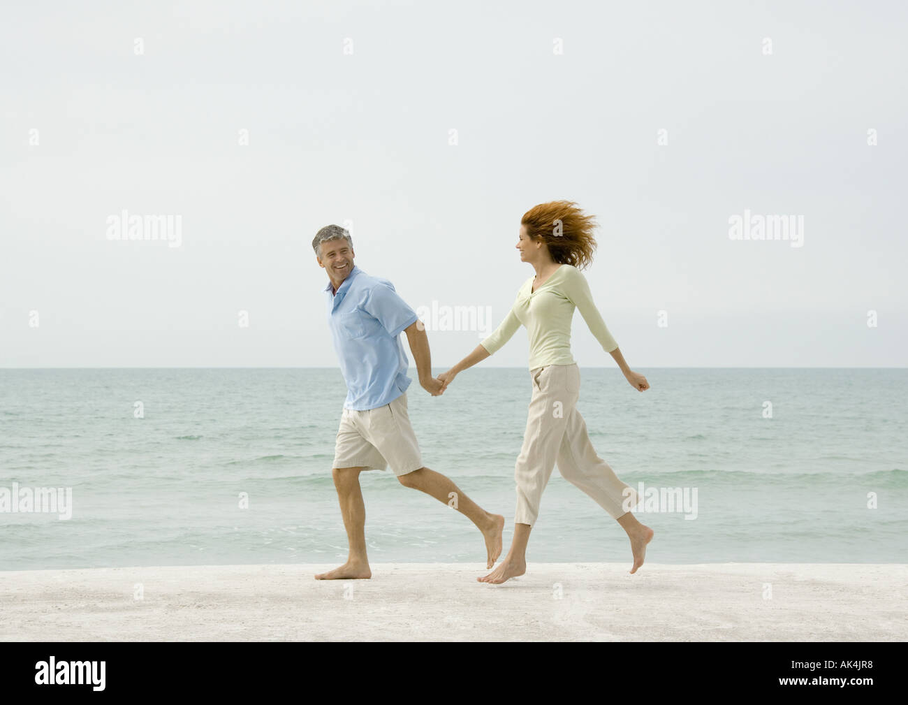 Mature couple running on beach Stock Photo