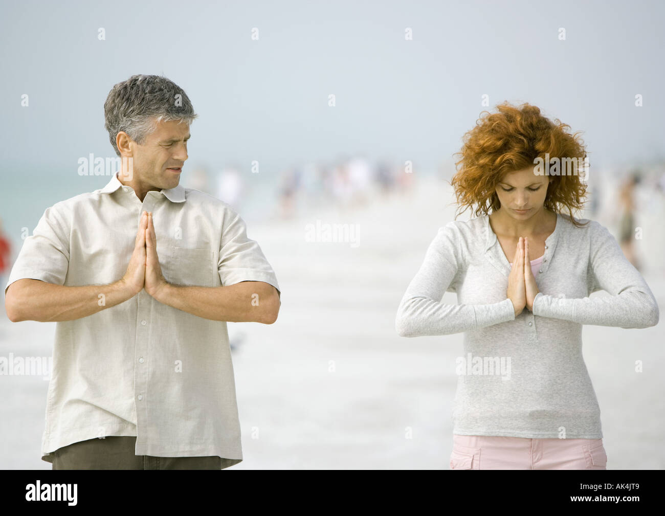 Couple meditating on beach Stock Photo