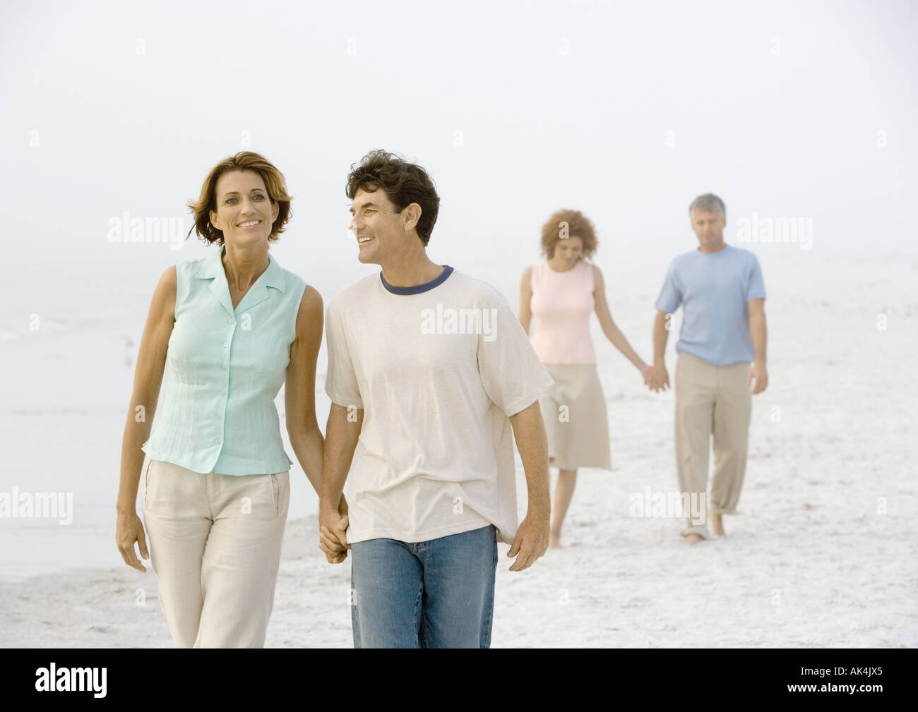 Two mature couples walking on beach Stock Photo