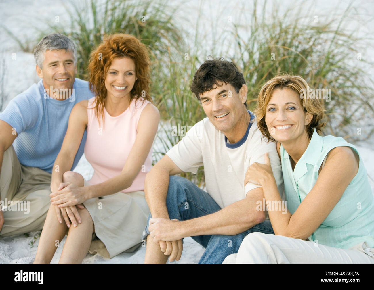 Two mature couples sitting on beach Stock Photo