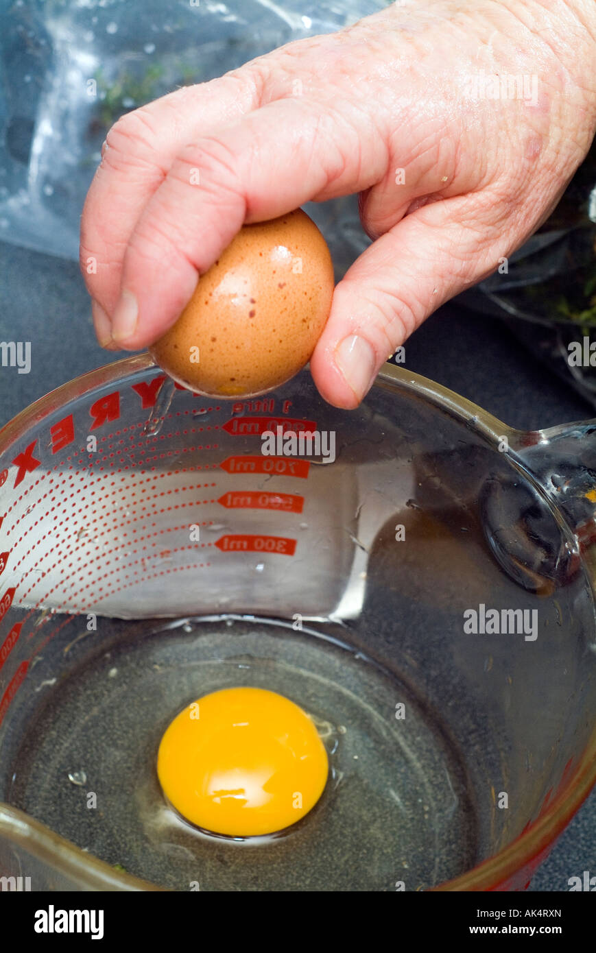 cracking eggs into jug Stock Photo