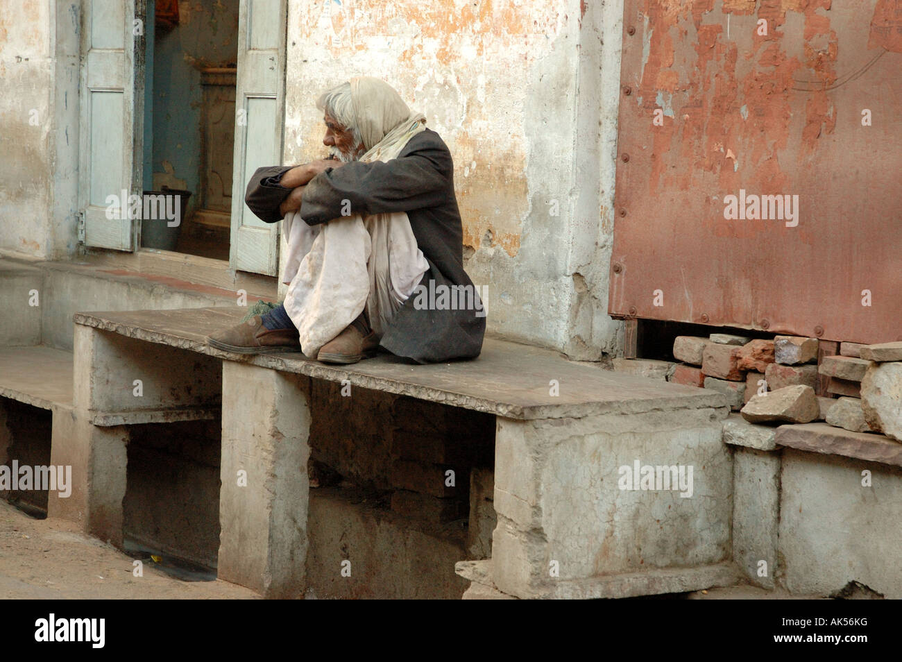 Old Man crouched on a bench in India Stock Photo