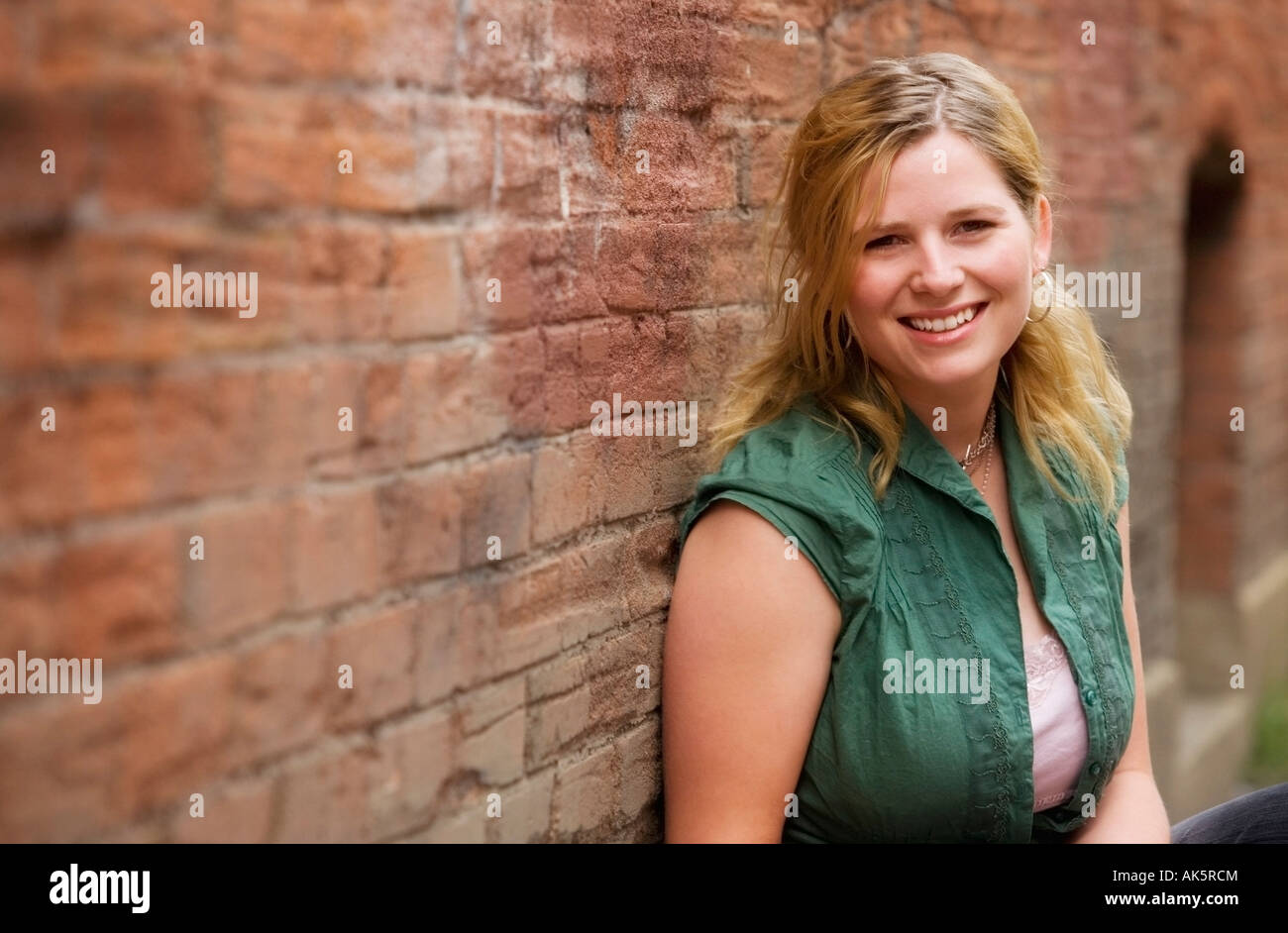 Woman standing in front of a brick wall Stock Photo - Alamy