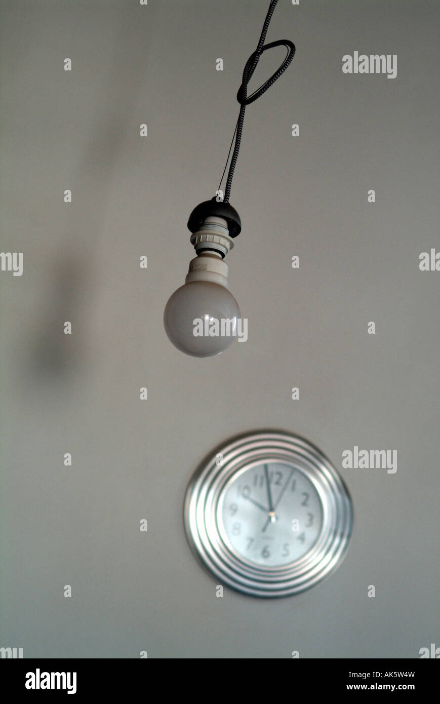 Lightbulb and wallclock inside home Stock Photo