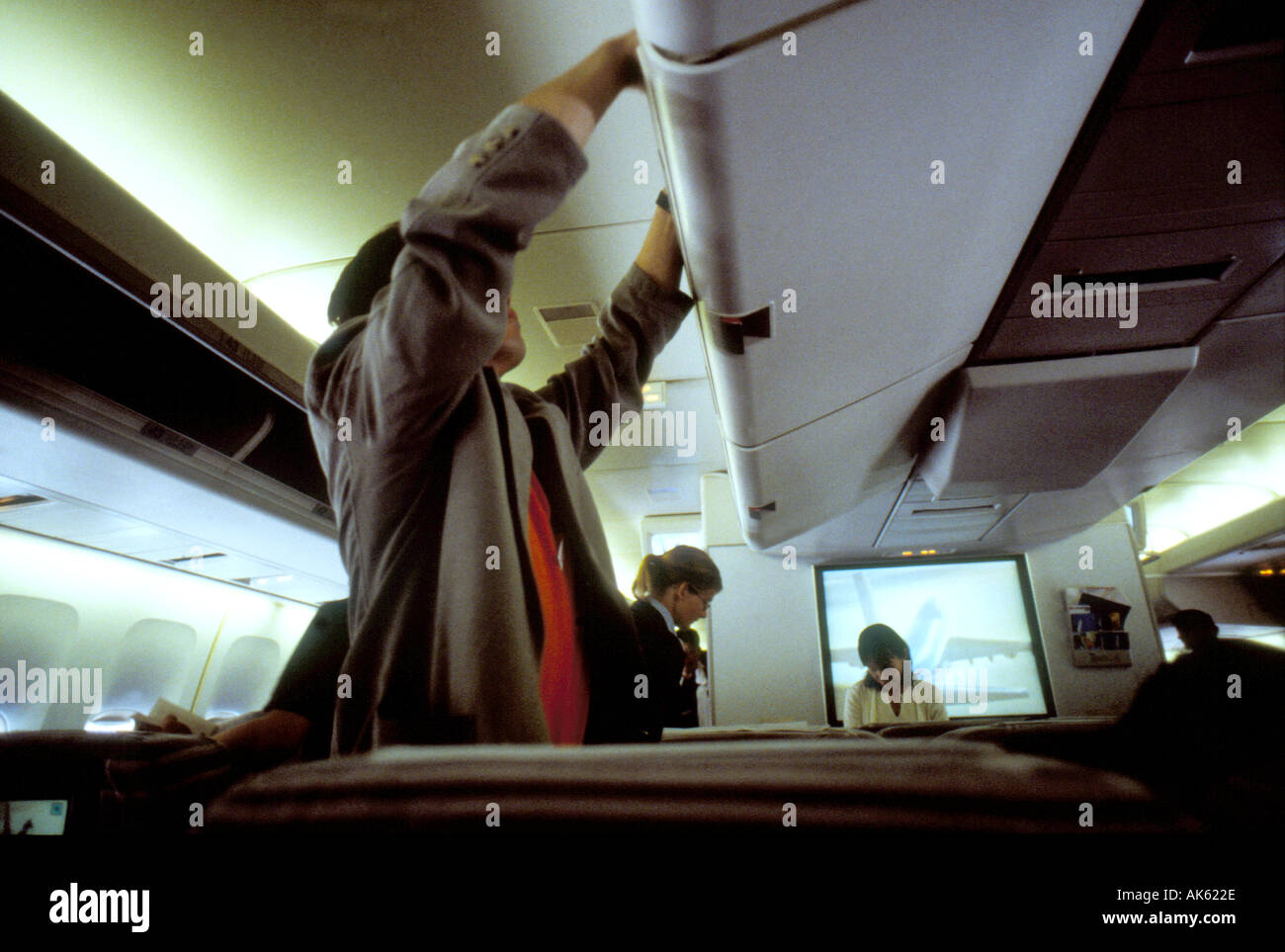 Passenger putting hand luggage in overhead locker on board aircraft