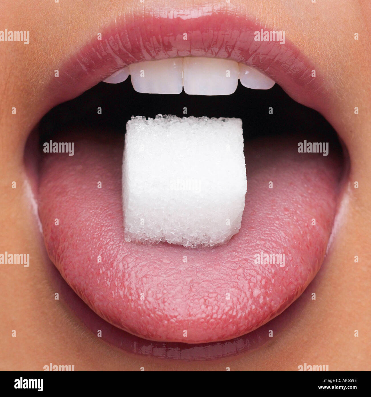 Piece of sugar on woman s tongue Zuckerwuerfel auf Zunge einer Frau Nahrungsmittel food quadratisch square Mund mouth Stock Photo