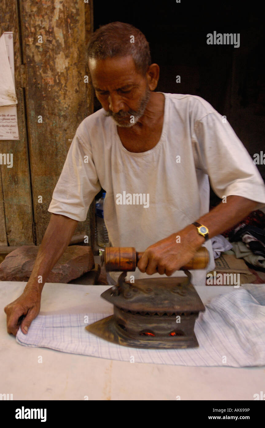 Ironing Man' Indian man ironing clothes for a living with coal iron in market. Bharatpur town. Rajasthan. INDIA Stock Photo