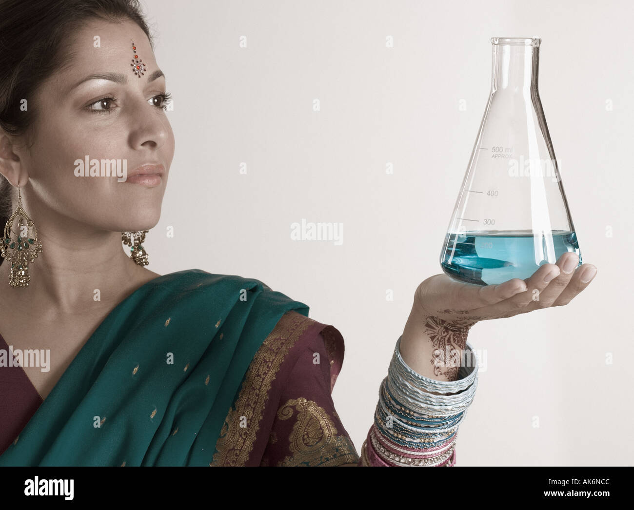 Young woman in traditional Indian dress holding a beaker Stock Photo