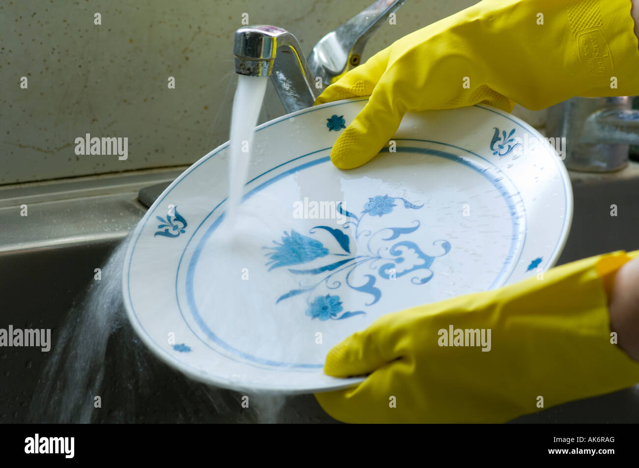 gloved hands washing dishes in kitchen sink Stock Photo