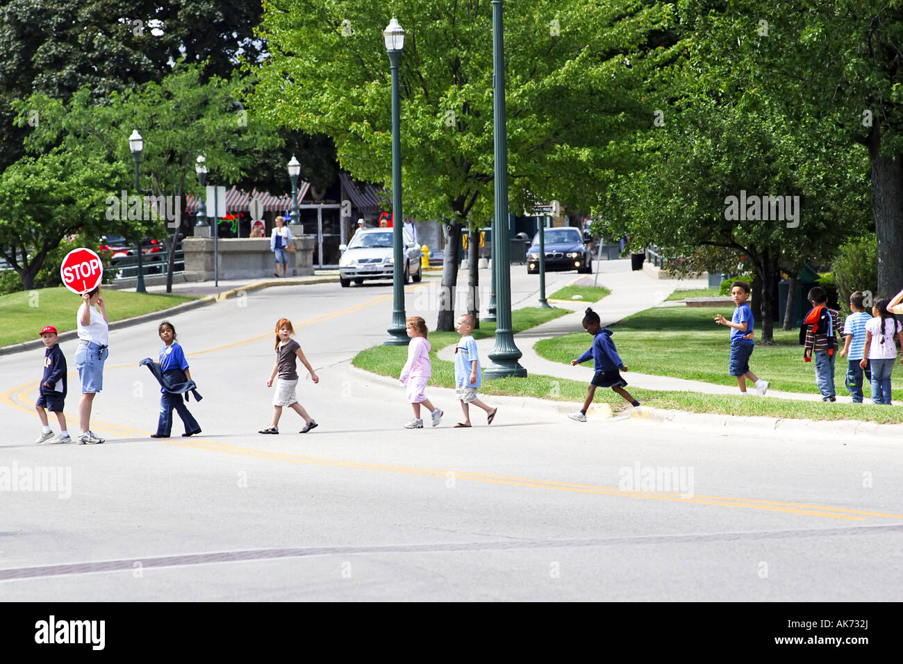 Children walking across the road whilst the traffic is stopped by a ...