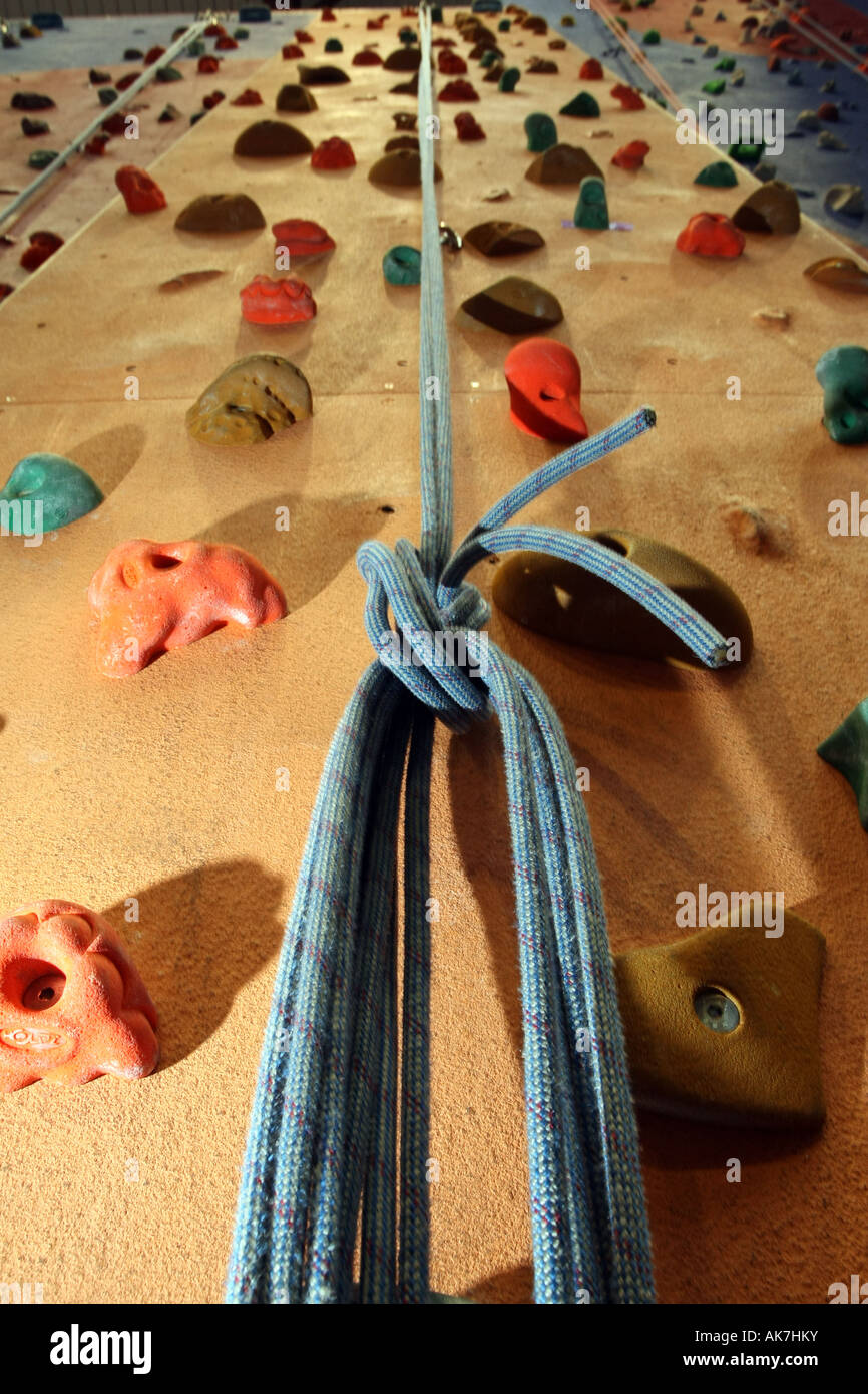 Hand holds bolted on to a climbing wall with a knotted rope looking up the wall Stock Photo