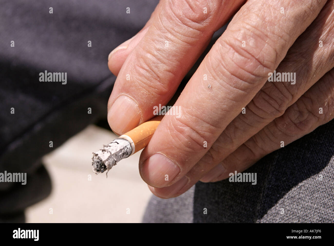 burnt down cigarette between two fingers Stock Photo Alamy