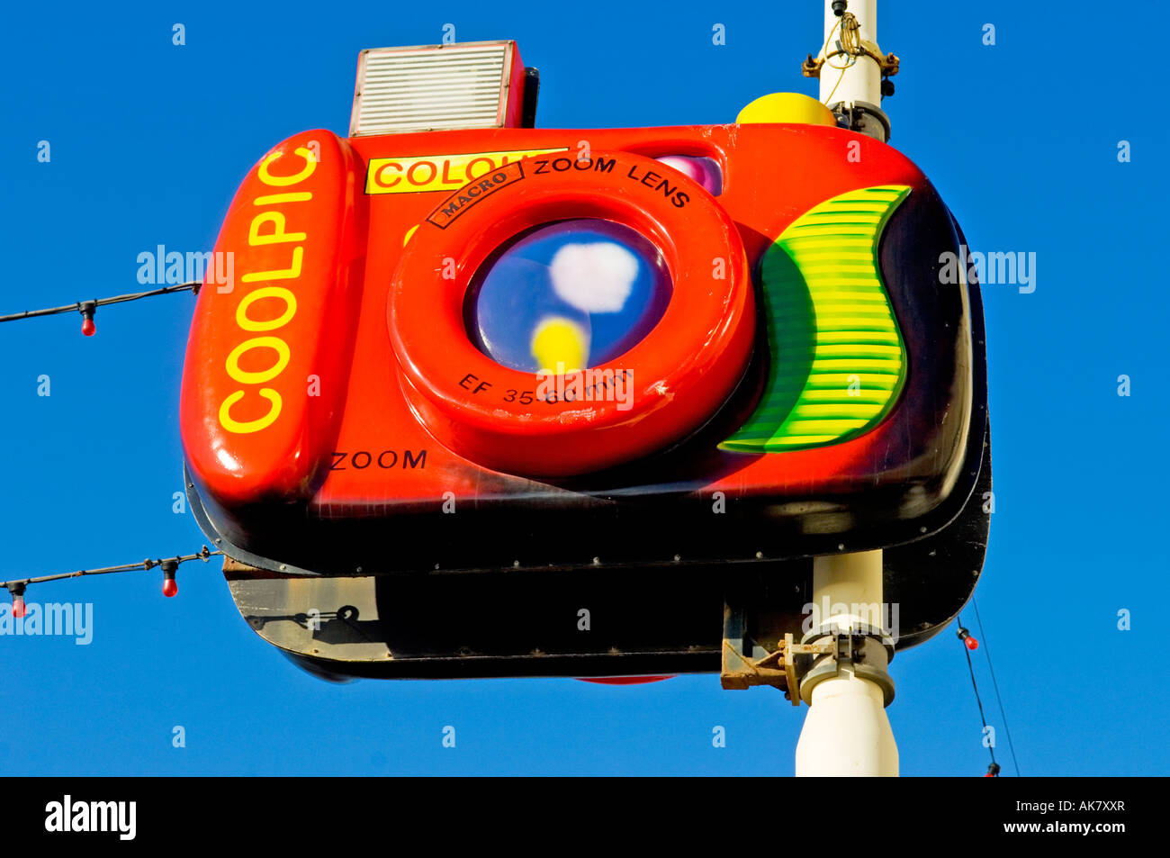 Giant plastic camera suspended from pole against blue sky in summer Stock Photo
