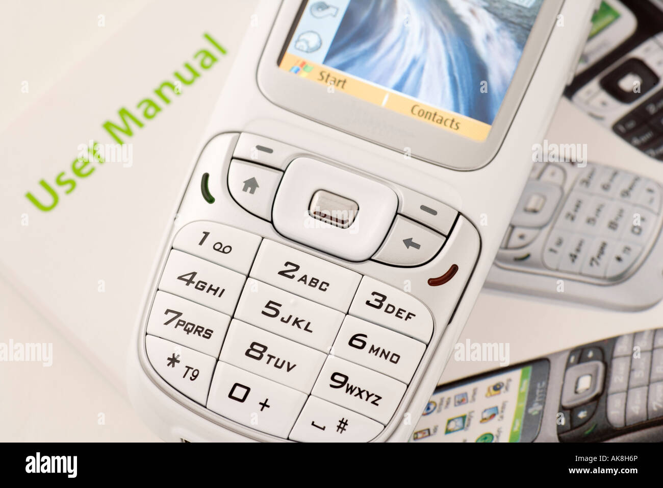 User manual and close up of numbers and symbols on keys on the keypad of a white mobile phone Stock Photo
