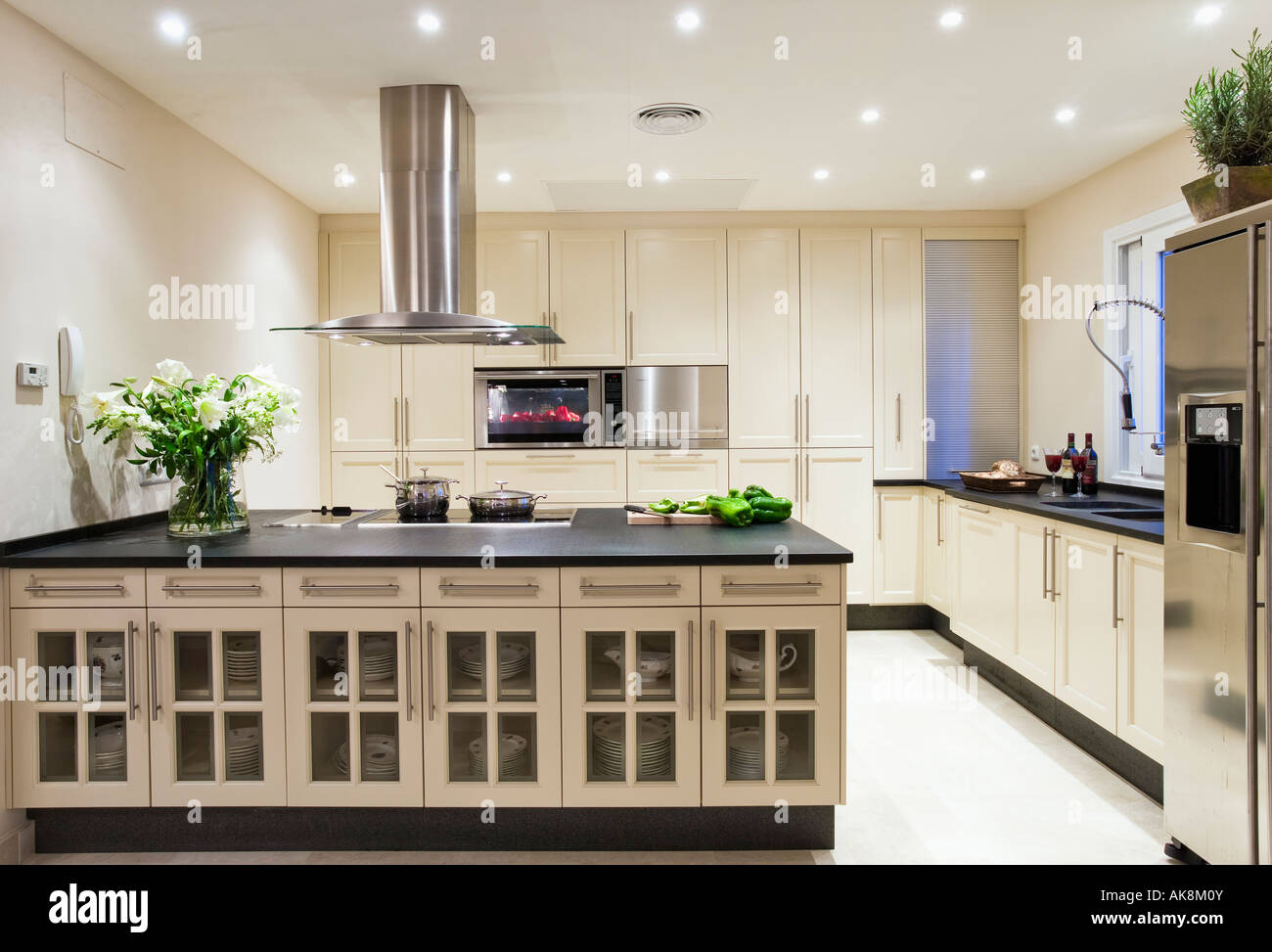 Stainless steel extractor hood above large island unit in modern white Spanish  kitchen with white flooring Stock Photo - Alamy