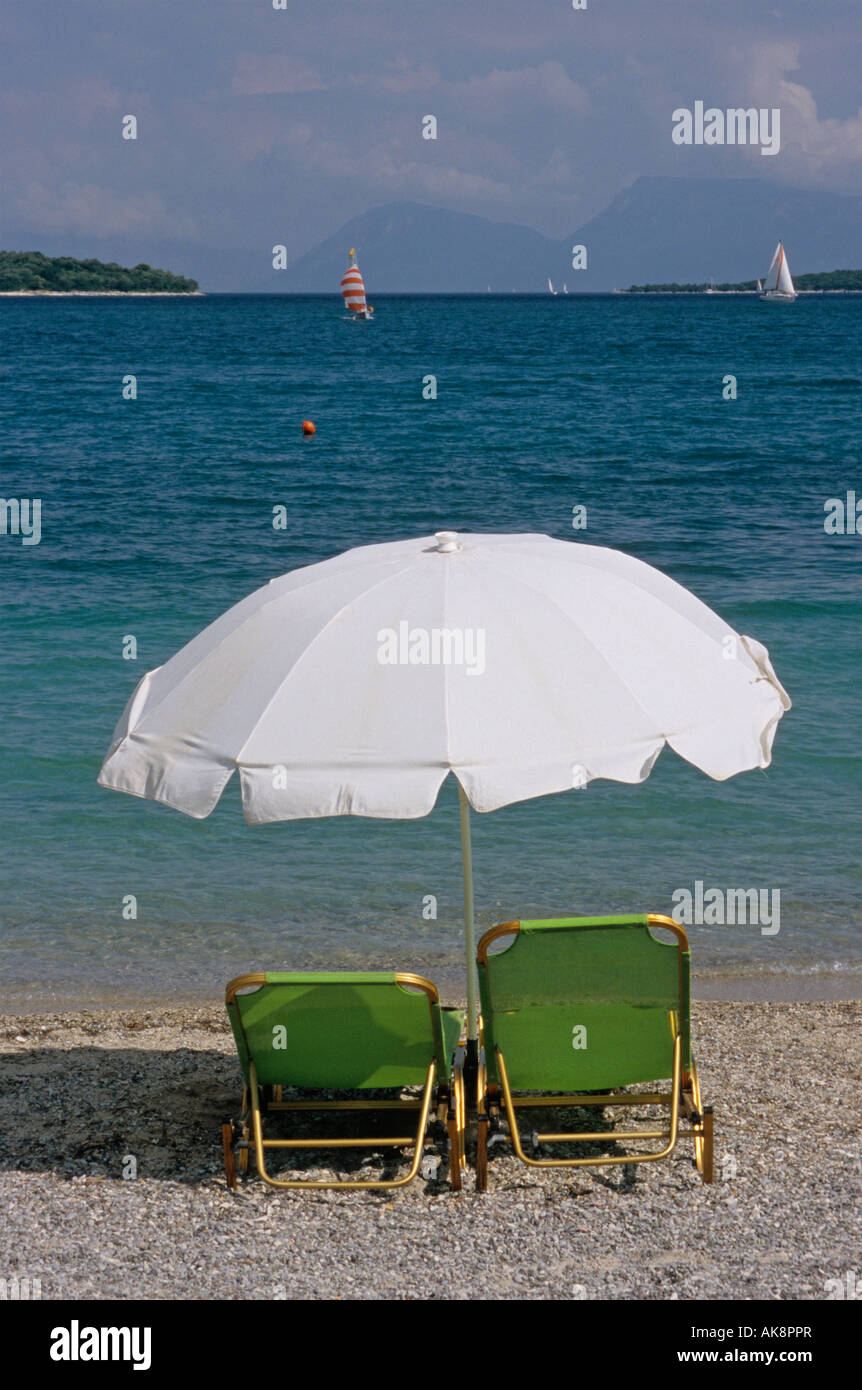 a pair of sunbeds under a parasol Nidri Cephalonia Island Greece Stock Photo