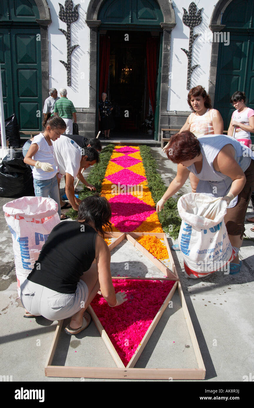 women making carpet from dyed wood shavings outside church in preparation for local fiesta on Sao Miguel island in The Azores Stock Photo