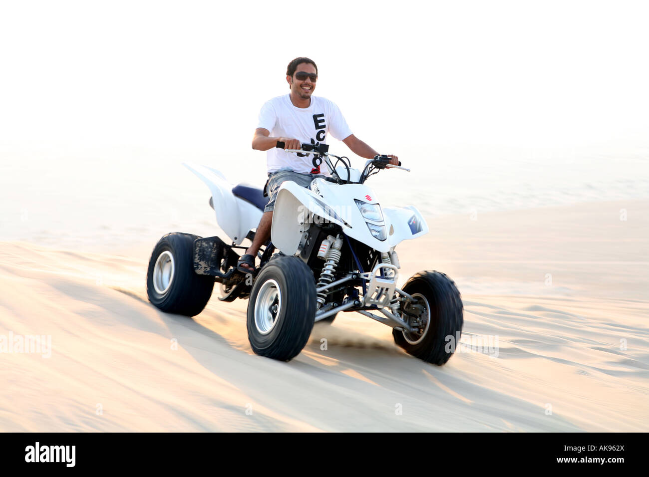 A young Qatari Arab man riding in the Qatari desert on a quadbike Stock Photo