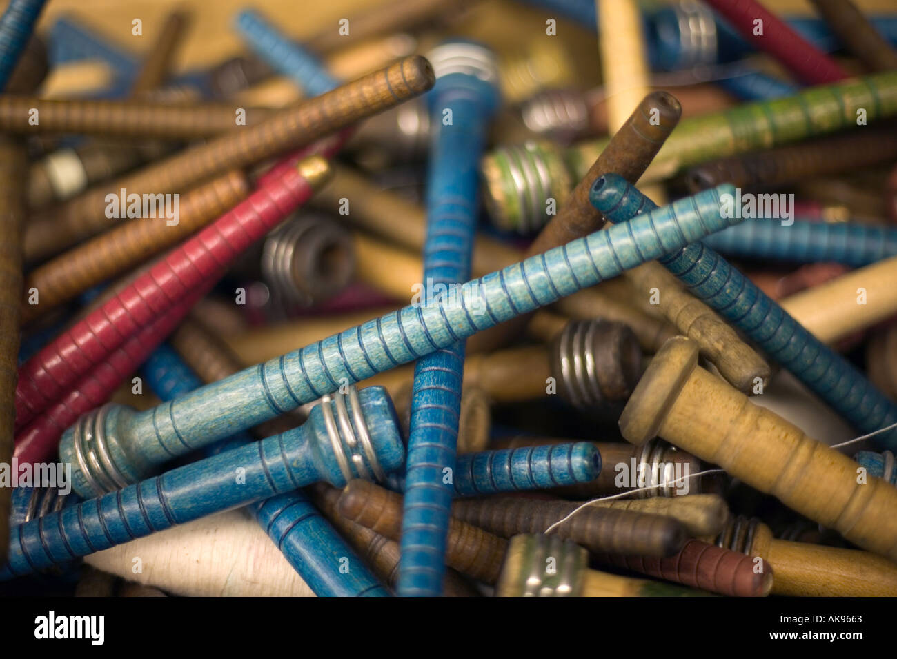 Colored wooden thread spindles from garment industry colorful and empty past their useful life laying every which way in pile Stock Photo