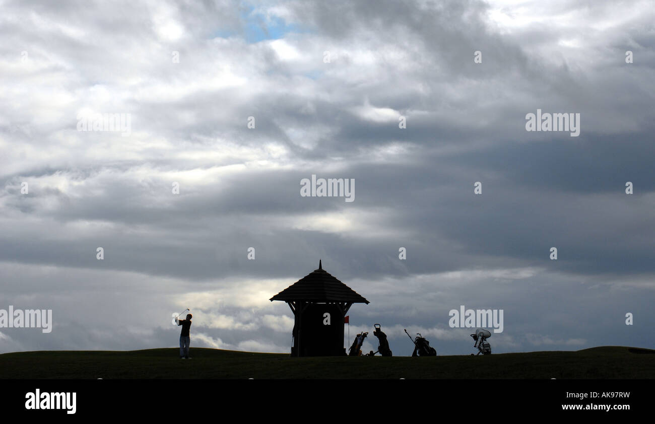 A GOLFER PLAYING A LATE EVENING ROUND OF GOLF ON A SCOTTISH GOLF COURSE,UK. Stock Photo
