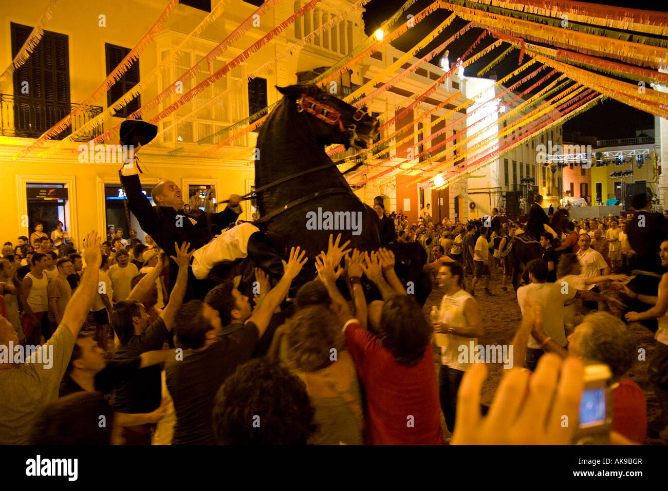 A rider rears his horse up on its back legs and holds his hat in the air at the fiesta in Mahon. Stock Photo