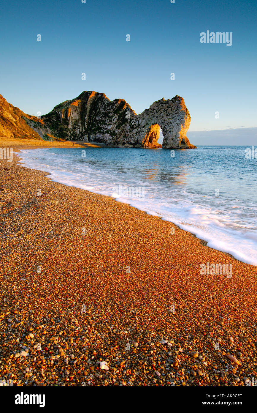 Warm light at sunset on the Dorset coast looking East towards Durdle Door with a clear blue sky Stock Photo