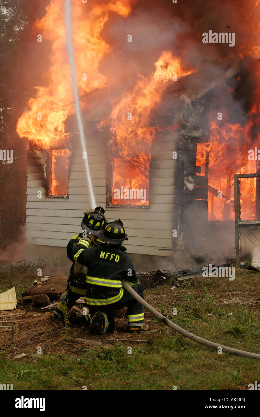 Two firefighters putting water on a house fire Stock Photo