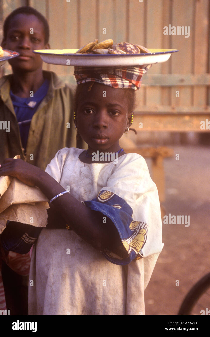 young girl in Burkina Faso carrying food on her head in a market place Stock Photo