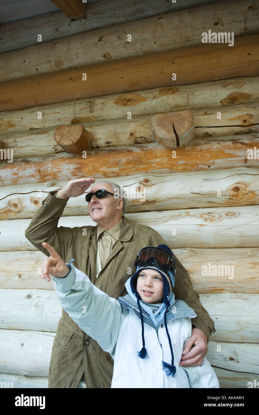 Grandfather and grandson standing together, boy pointing, both looking up Stock Photo