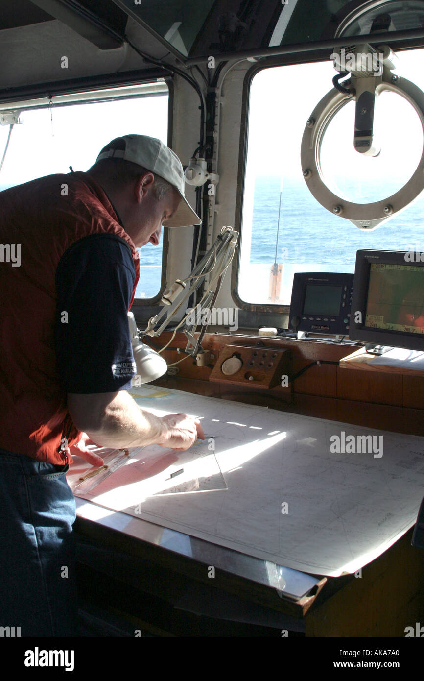 Navigation officer plotting a course at the navigation desk on the bridge of a ship. Stock Photo