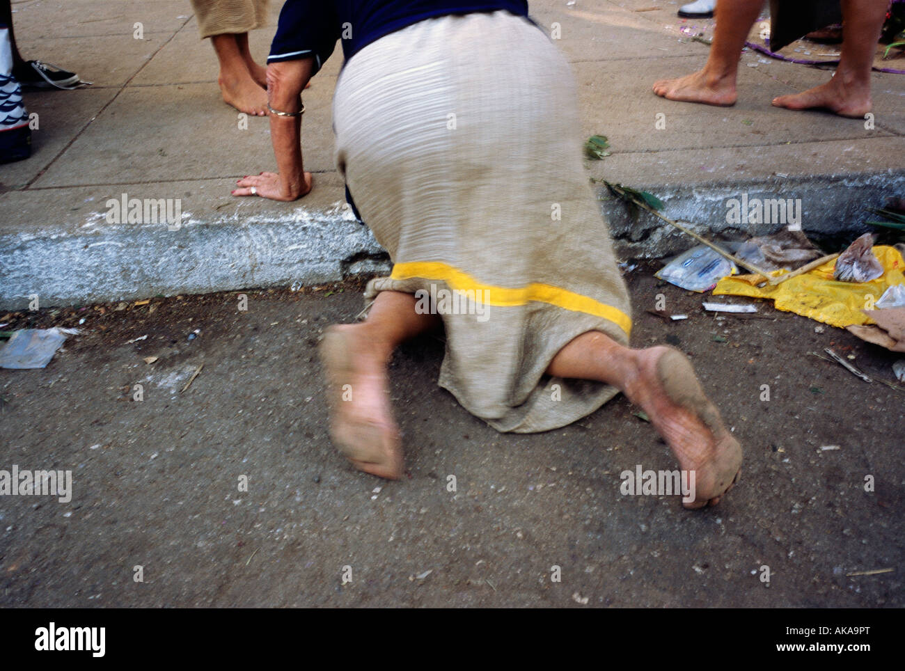 Devotee on hands and knees crawls ofer the curb in front of the Santuario de San Lazaro. Rincon Cuba Stock Photo