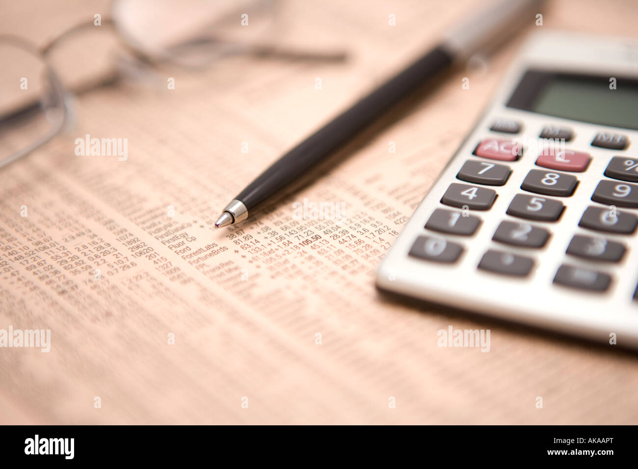 Financial newspaper calculating studying stocks and shares and financial markers for possible winners and losers Stock Photo