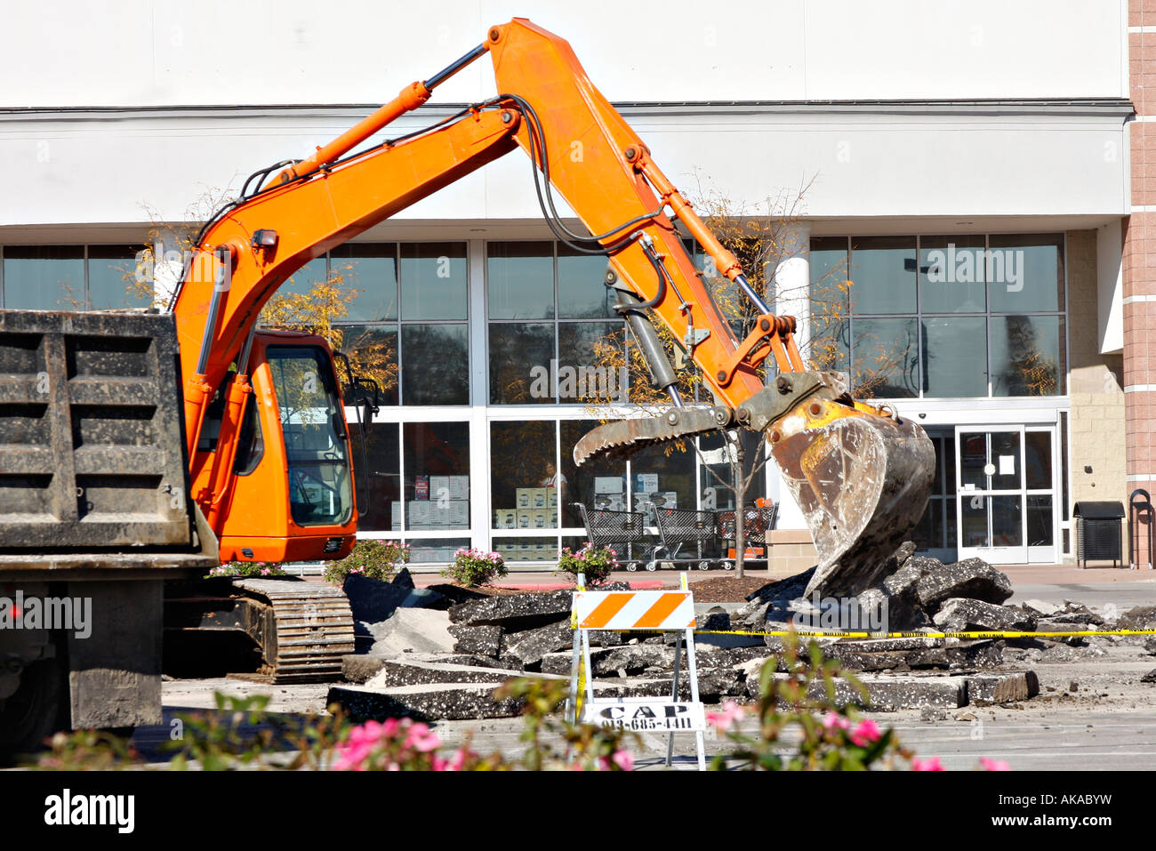 This is a picture of a backhoe tearing up the concrete in a parking lot