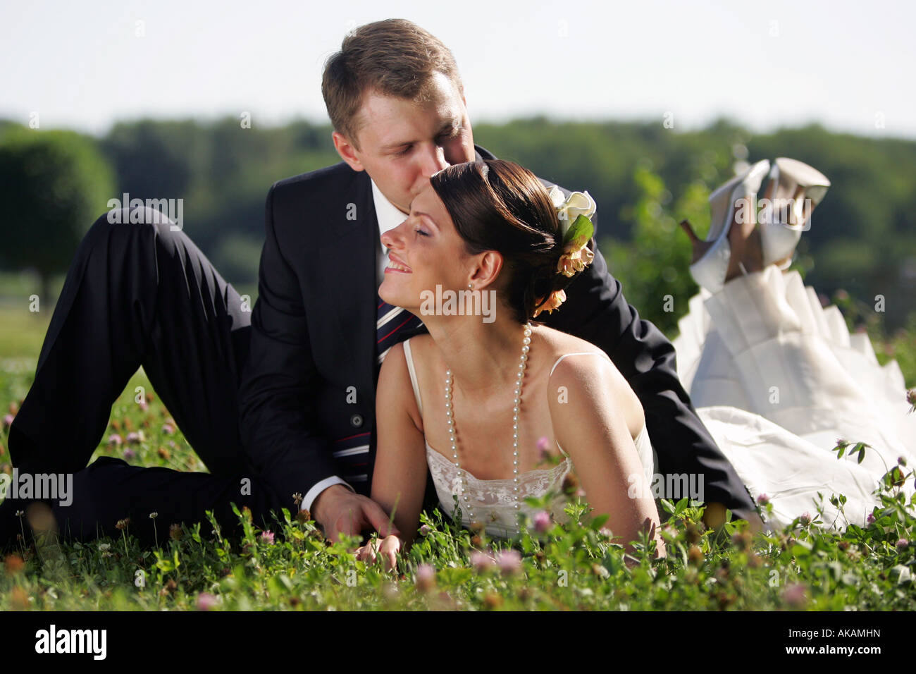 Newly married bride and groom kissing in field of flowers after wedding ceremony Stock Photo