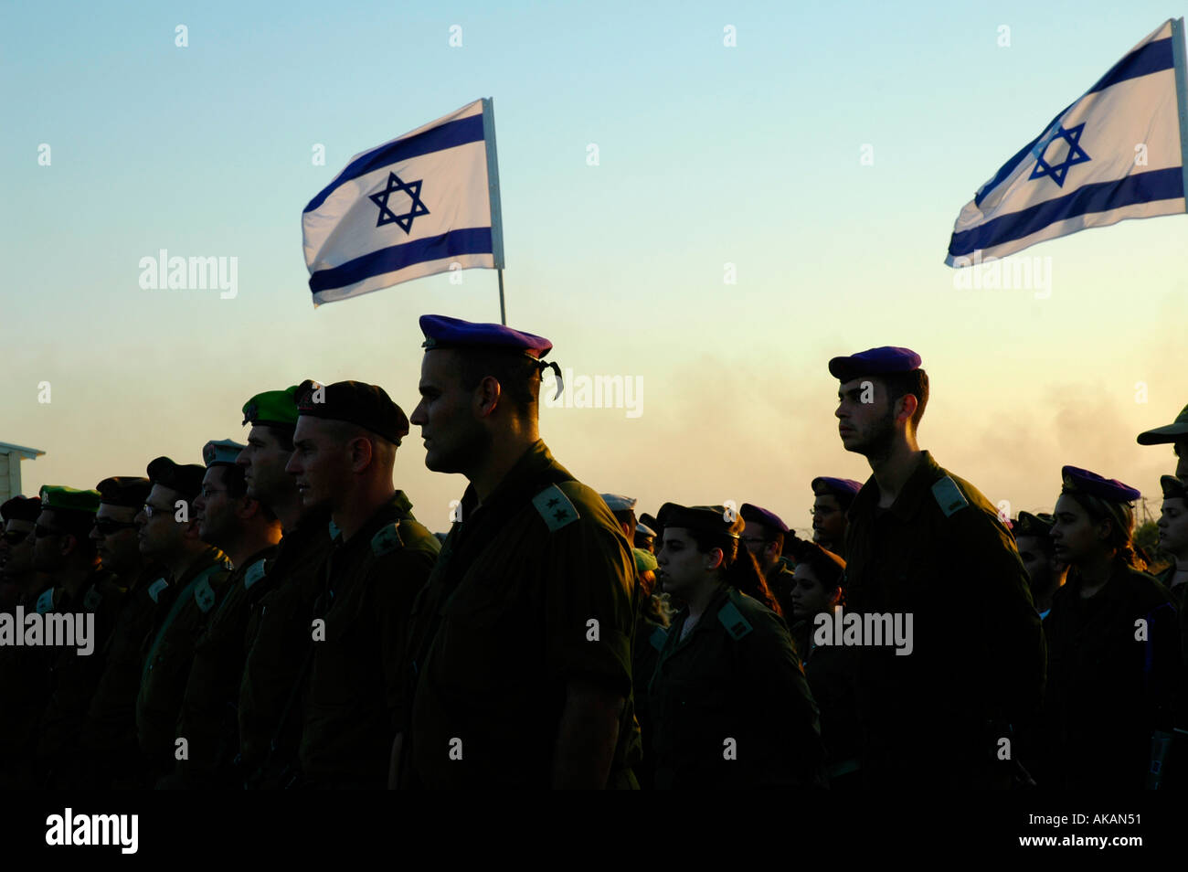 Silhouetted Israeli soldiers standing in formation with national flags flapping in the wind in Israel Stock Photo