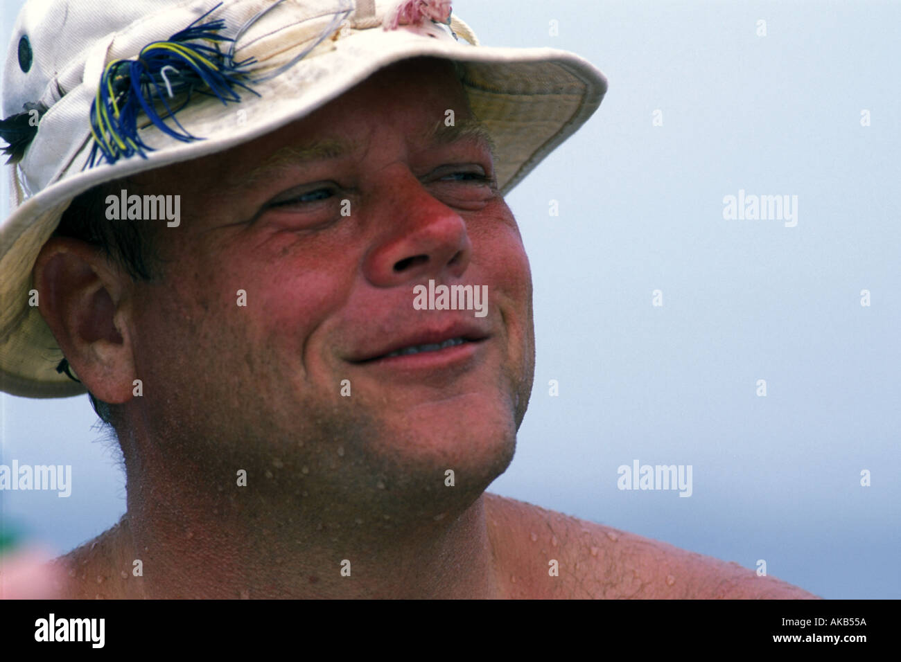 https://c8.alamy.com/comp/AKB55A/fishing-lures-dot-the-bucket-hat-of-a-relaxed-but-sunburned-sportsman-AKB55A.jpg