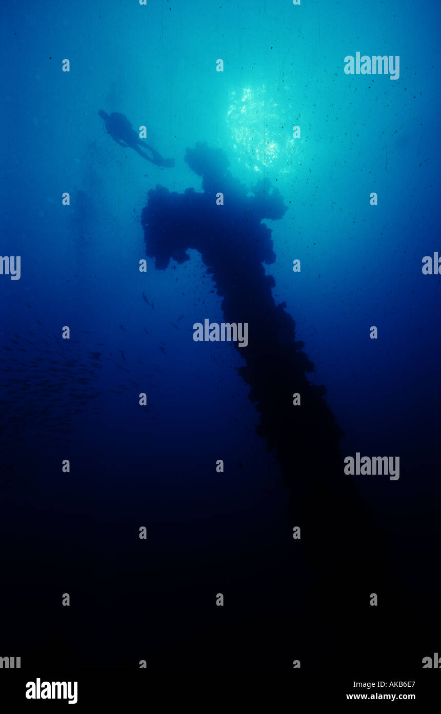 A scuba diver is dwarfed by the looming kingpost of the Unkai Maru shipwreck in Truk Lagoon Stock Photo