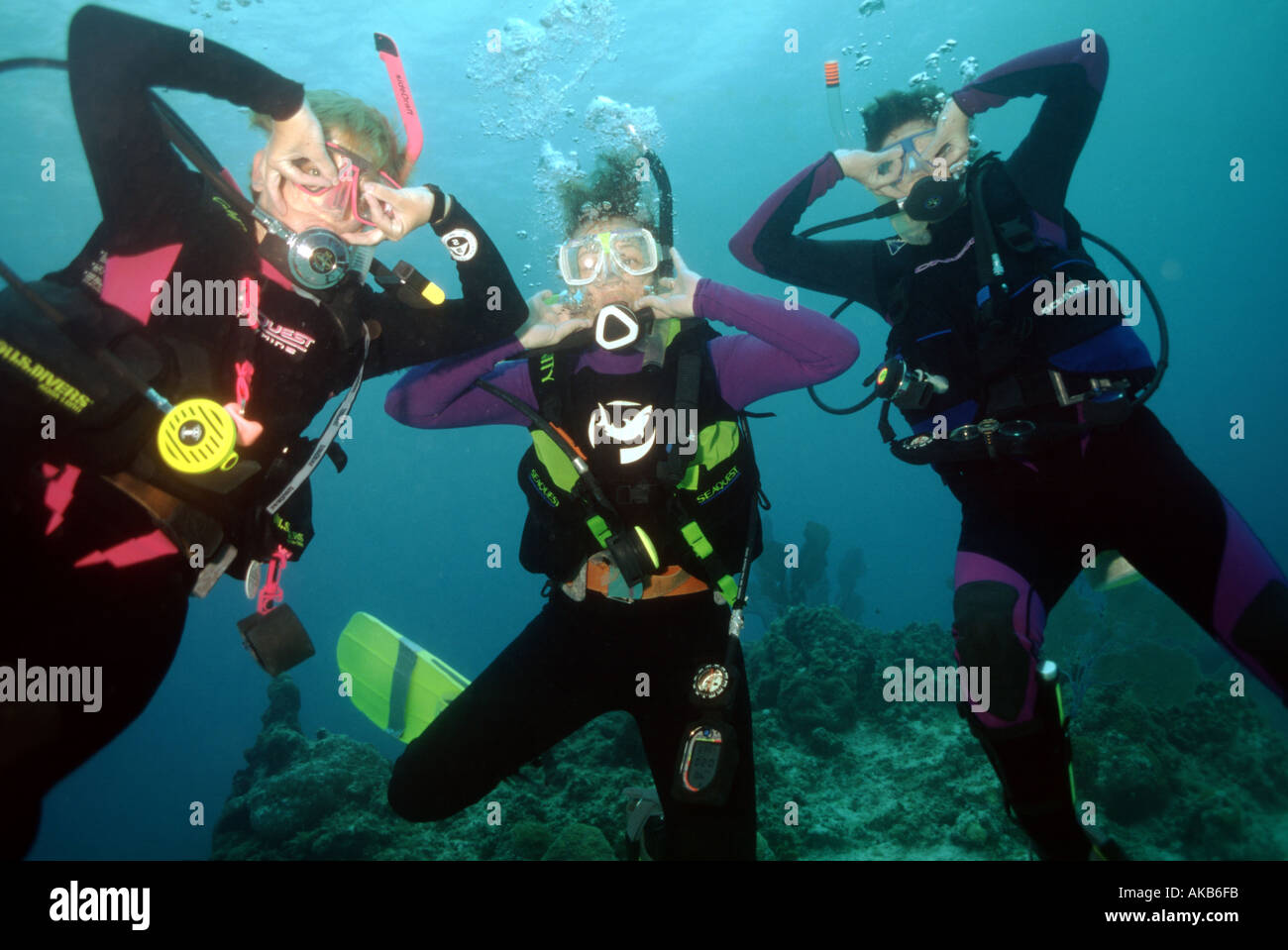 Hand signals and scuba diving in the blue Caribbean ocean can be fun and silly when there are three friends with whom to play am Stock Photo