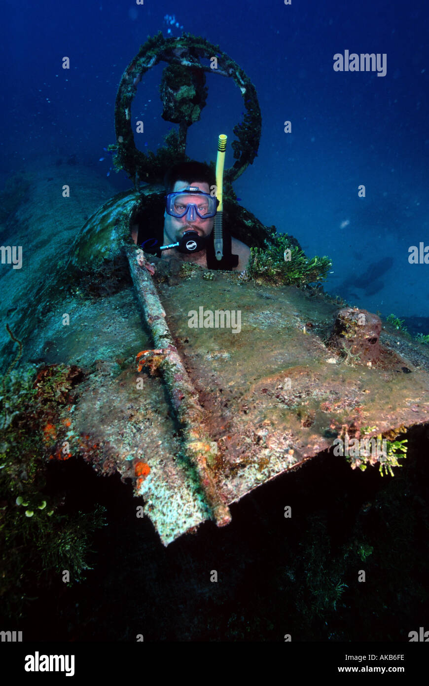 A male scuba diver sits inside the airplane wreck of the Betty Bomber in Truk Lagoon Micronesia Stock Photo