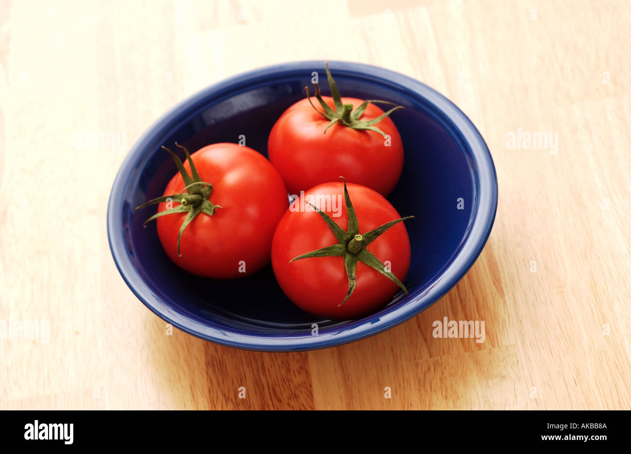 Three tomatoes in a bowl Stock Photo